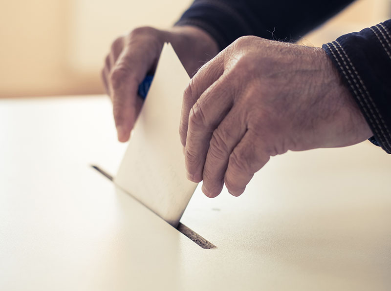 Photo d’un homme déposant un bulletin de vote dans une urne