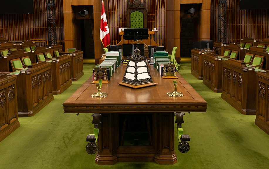 The Clerk’s Table and the Speaker’s Chair directly behind it, provide focus and direction for Members of Parliament in the Chamber, as they situate the individuals that all Members look to, address, and seek counsel from during proceedings. 