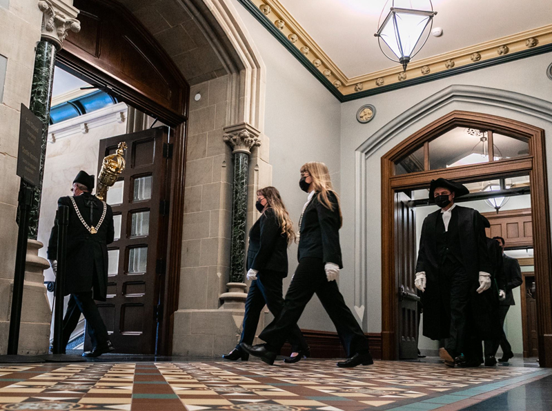 Le sergent d’armes (portant la masse) et le Président arrivent dans la salle du Sénat pour la lecture du discours du Trône