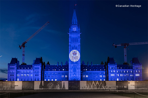 Parliament Building illuminated in royal blue with the royal cypher projected on the Peace Tower 