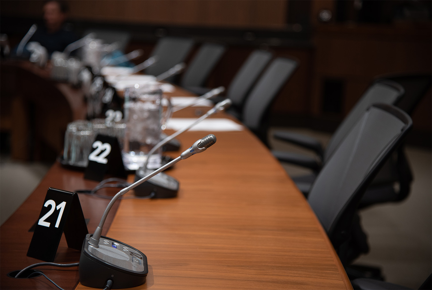 Committee table with a row of numbered microphones.